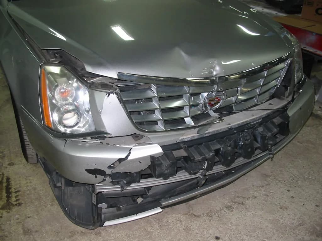 Close-up of Cadillac front bumper and grille damage before collision restoration