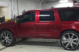 Red Ford Excursion side profile with mirror-finish chrome custom wheels at Jack's