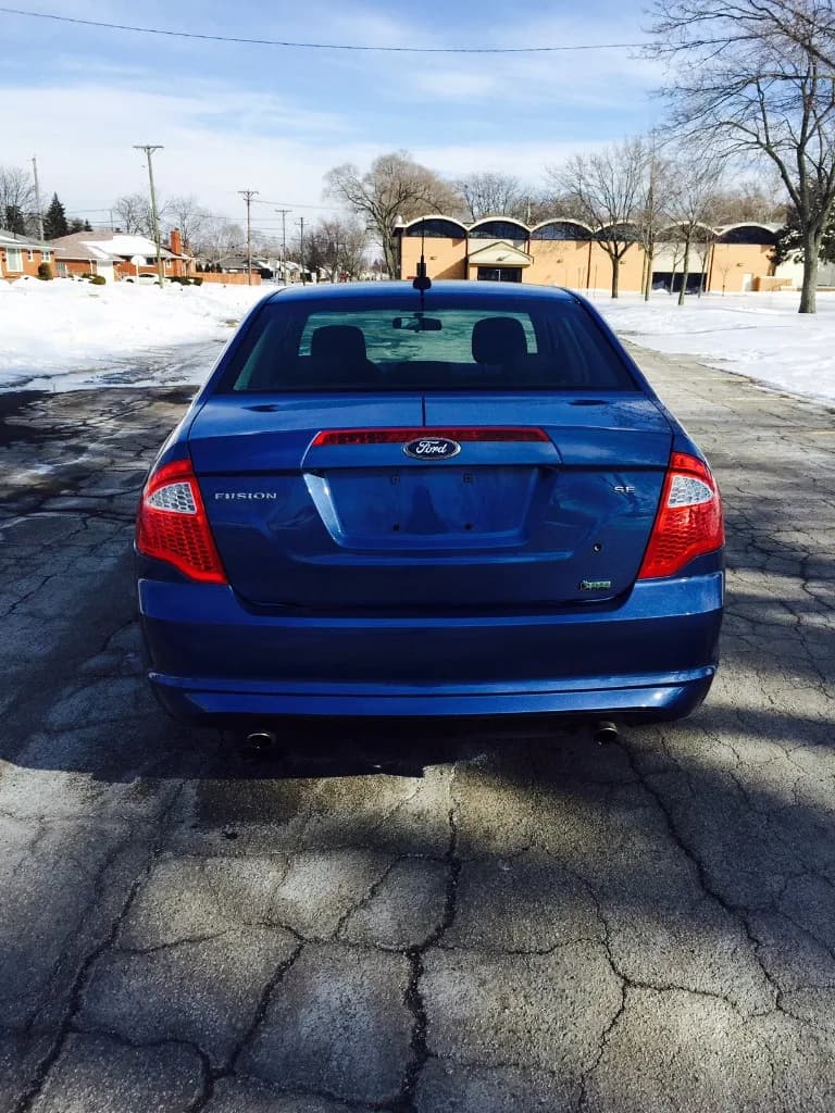 Blue Ford Fusion sedan after repair — rear view with clean finish