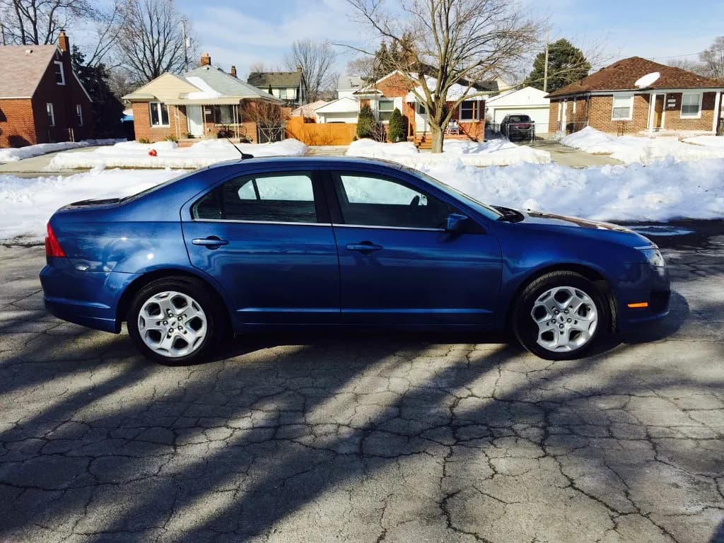 Blue Ford Fusion with alloy wheels after body repair — clean side profile finish